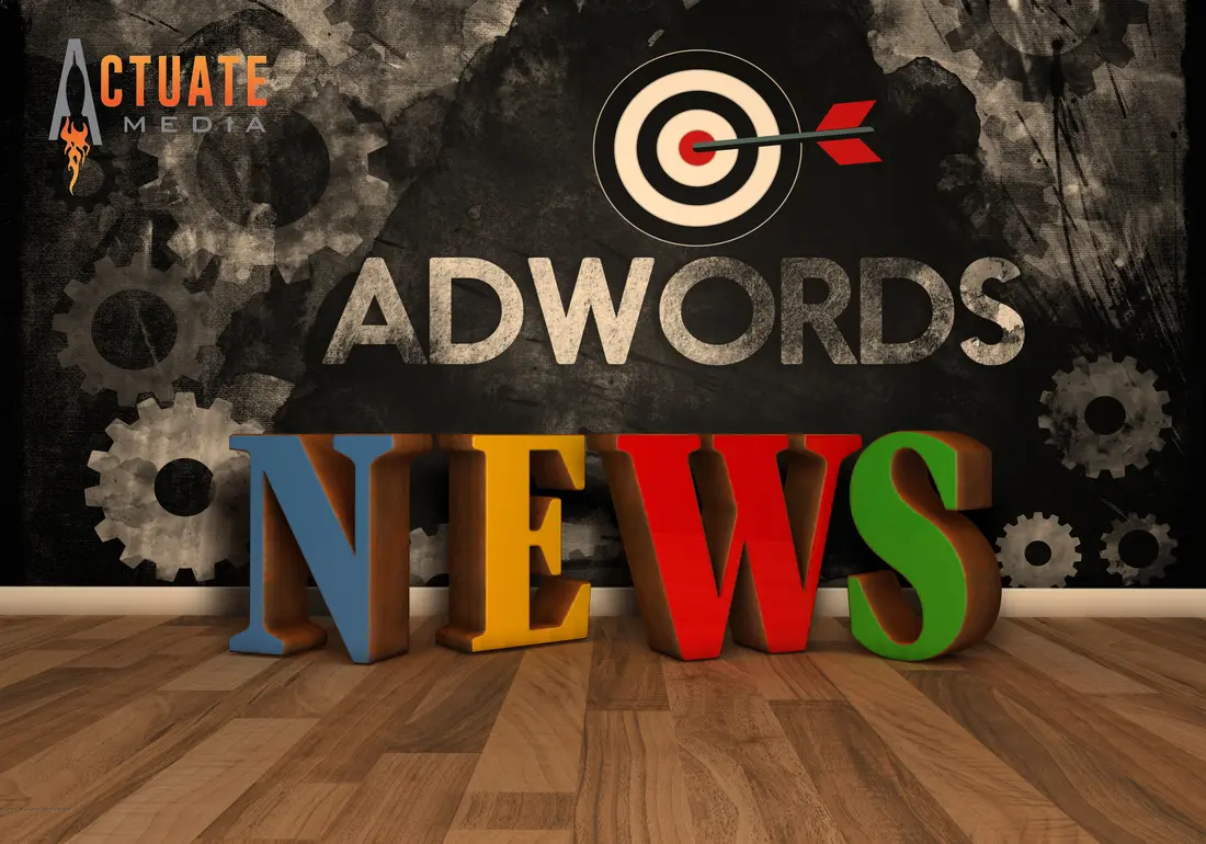 Colorful 3D block letters spelling "NEWS" on a wood floor in front of a chalkboard wall reading "ADWORDS" with a dartboard and arrow