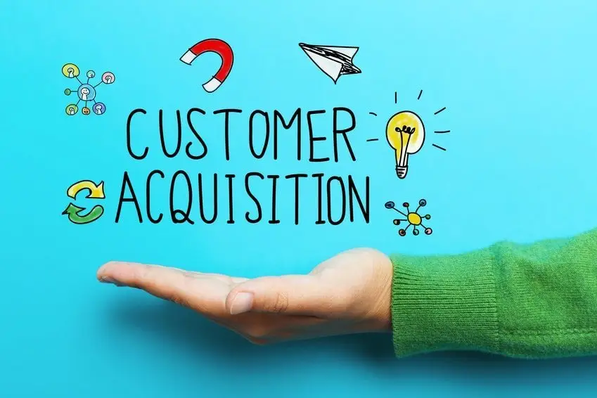Open upturned palm in a green sweater beneath hand-drawn text "Customer Acquisition" with doodled magnet, paper plane and lightbulb icons on turquoise