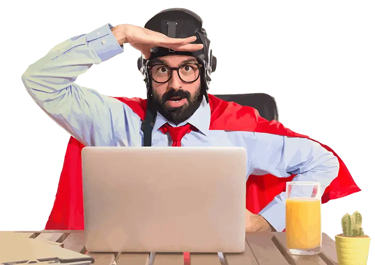 Bearded man in a red cape and leather flying cap shields his eyes with one hand, peering over a laptop on a wooden desk.