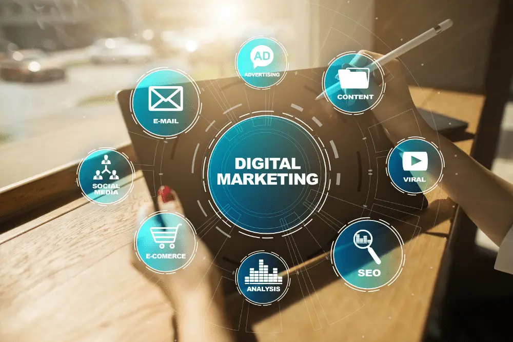 Hands holding a tablet with a teal "Digital Marketing" hub ringed by E-mail, Social Media, SEO, E-commerce and Ad icons.
