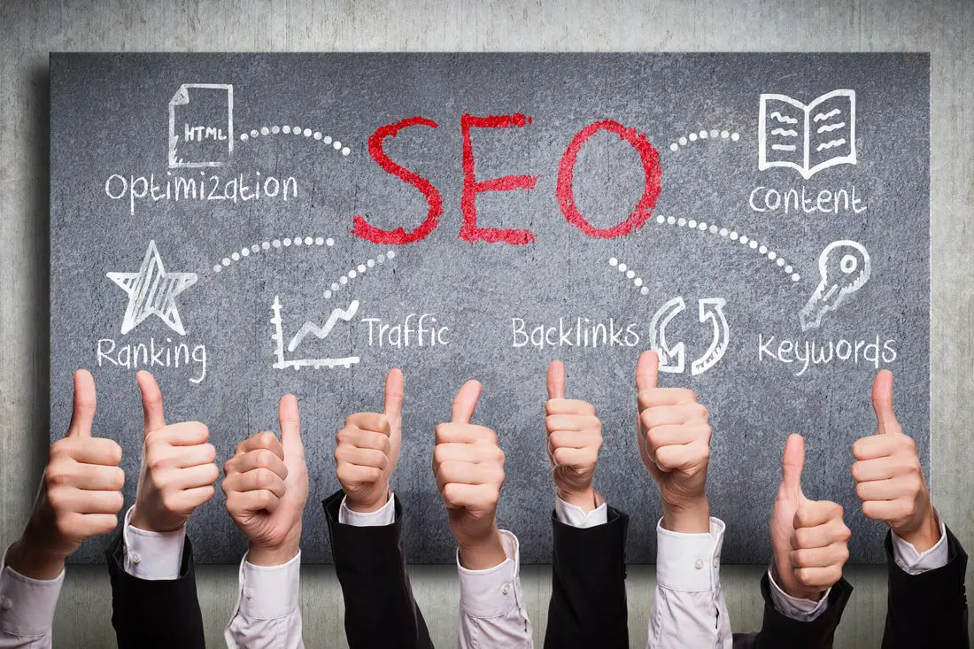 Row of suited arms giving thumbs up in front of a chalkboard reading "SEO" with "Optimization," "Traffic," "Backlinks" and "Keywords"
