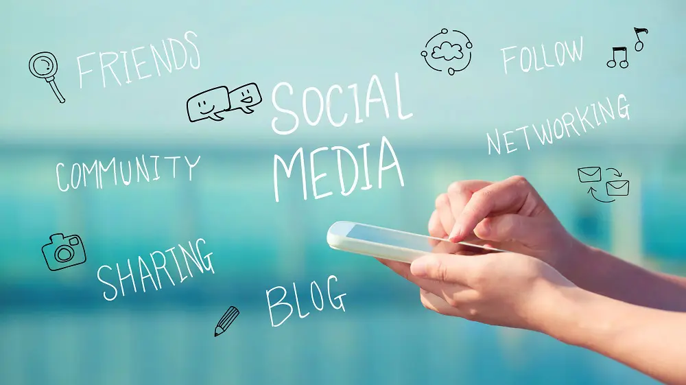 Hands holding a smartphone against a blurred teal background with handwritten words "Social Media," "Friends" and "Networking" and doodle icons